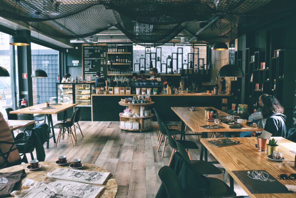 Cafe with dark colours and wooden floor and tables.